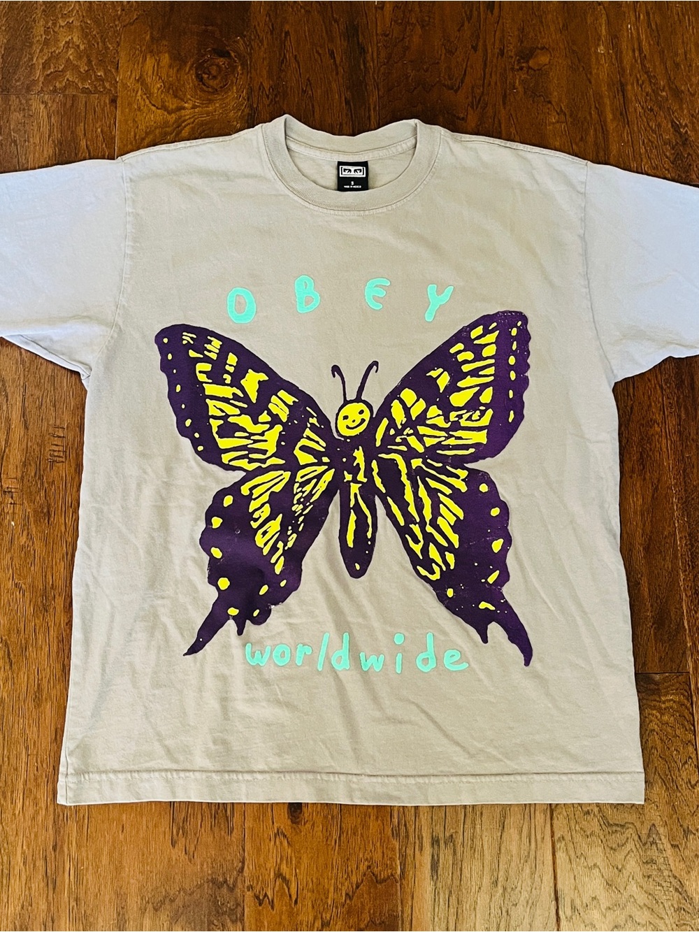 Obey Beige Tee with Purple and Yellow Butterfly Graphic